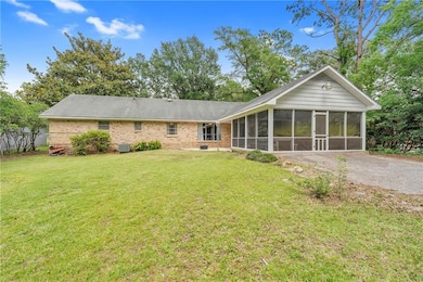 Rear view of property with a sunroom, brick siding, a yard, and cooling unit