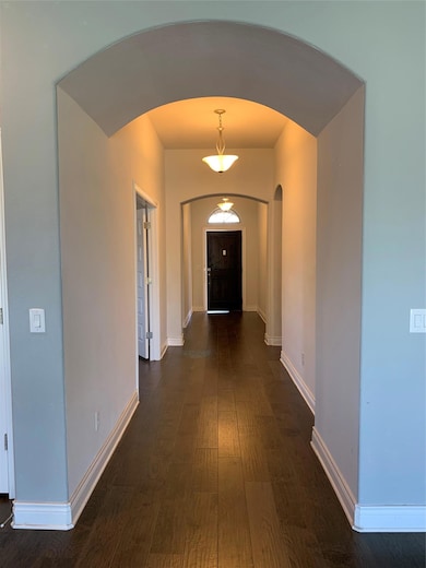 Hallway featuring arched walkways and dark wood f