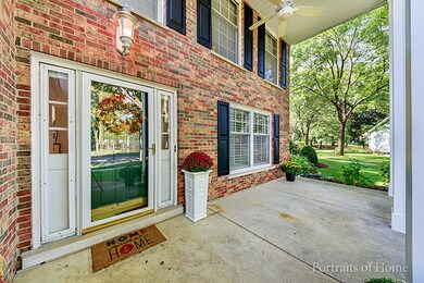 Covered front patio with ceiling fan. Exposed bric