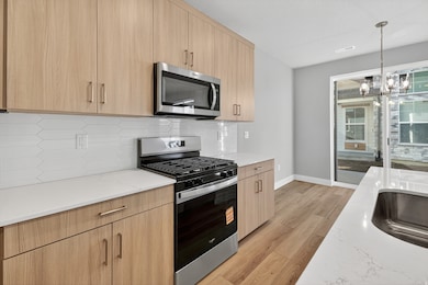 Kitchen with appliances with stainless steel finishes, modern cabinets, light brown cabinetry, and light wood-style floors