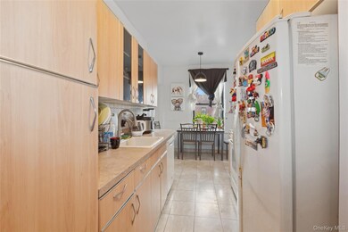 Kitchen with freestanding refrigerator, light brown cabinetry, a sink, and light countertops