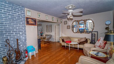 Living area featuring wood finished floors, a textured ceiling, and a ceiling fan