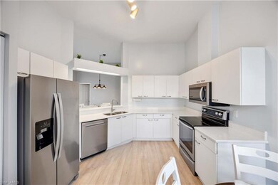 Kitchen with pendant lighting, a high ceiling, sink, appliances with stainless steel finishes, and white cabinetry