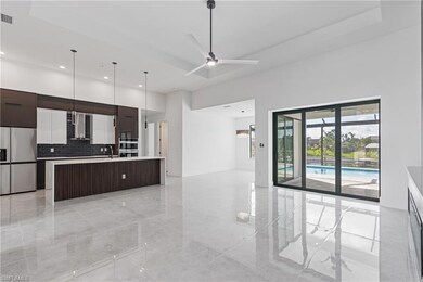Kitchen featuring ceiling fan, stainless steel fridge, dark brown cabinets, a center island with sink, and backsplash