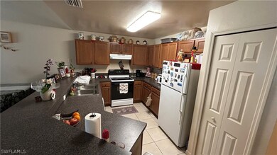 Kitchen with sink, white appliances, and light tile floors