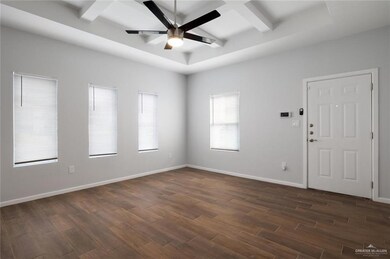 Empty room featuring dark wood-type flooring, ceiling fan, and beamed ceiling
