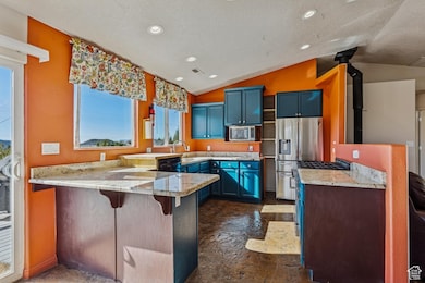 Kitchen featuring blue cabinetry, a peninsula, recessed lighting, a kitchen breakfast bar, and light stone countertops