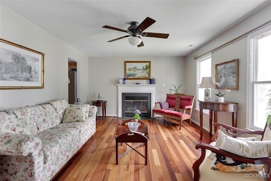 Living area featuring wood finished floors, a ceiling fan, and a fireplace with flush hearth
