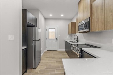 Kitchen with appliances with stainless steel finishes, a sink, baseboards, modern cabinets, and recessed lighting