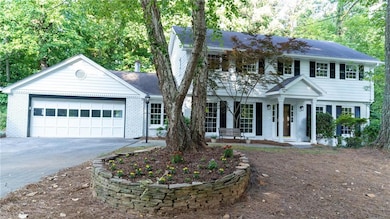 View of front of home with brick siding, driveway, a garage, and covered porch