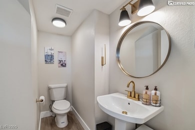 Bathroom with wood finished floors, toilet, basebo
