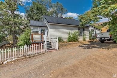 View of front of home featuring a metal roof, dirt driveway, and cooling unit