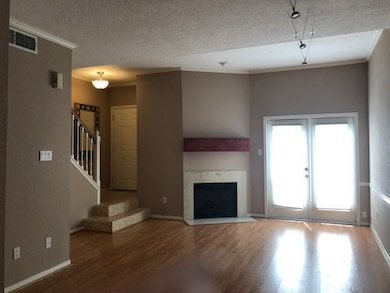 Stepping down from the entryway, you will see  into the gleaming floors of your living room with a cozy fireplace and french doors which lead to a small patio area.