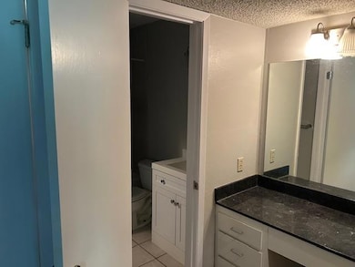 Bathroom with vanity, toilet, a textured ceiling,