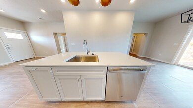 Kitchen featuring stainless steel dishwasher, a kitchen island with sink, white cabinetry, and recessed lighting