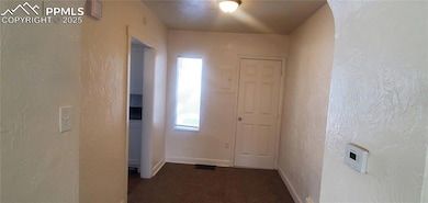 Corridor featuring carpet flooring, baseboards, and a textured wall