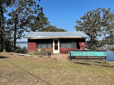 View of front of house with a front yard, a deck with water view, and a metal roof