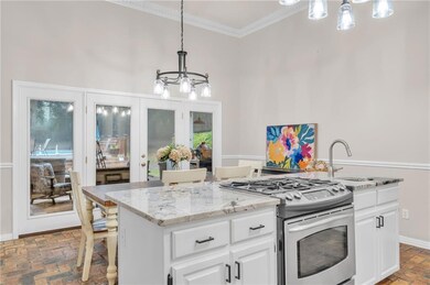 Kitchen with stainless steel gas range oven, a chandelier, brick flooring, crown molding, and a center island