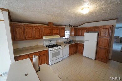 Kitchen featuring range hood, visible vents, a sink, white appliances, and brown cabinetry