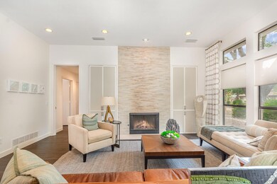 Living room with a tile fireplace, visible vents, 