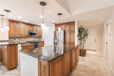 Kitchen with a kitchen island, appliances with stainless steel finishes, and decorative light fixtures