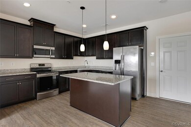 Kitchen featuring light hardwood / wood-style floors, dark brown cabinetry, pendant lighting, and stainless steel appliances