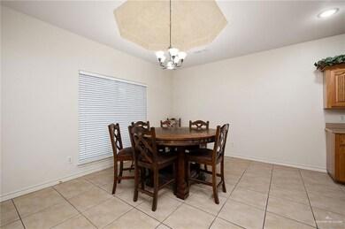 Tiled dining area featuring a tray ceiling and a chandelier
