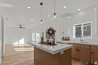 Kitchen featuring brown cabinets, a center island, pendant lighting, light wood-style flooring, and recessed lighting.