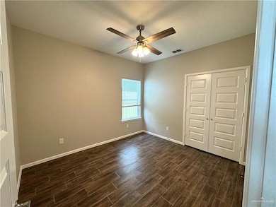 Unfurnished bedroom with dark wood finished floors, a closet, baseboards, and a ceiling fan