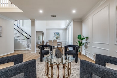 Living area featuring ornamental molding, arched walkways, light wood finished floors, stairs, and recessed lighting