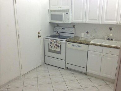 Kitchen featuring white appliances, a sink, white cabinetry, light tile patterned floors, and backsplash