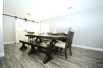 Spacious dining room with custom built coat closet behind sliding barn door.