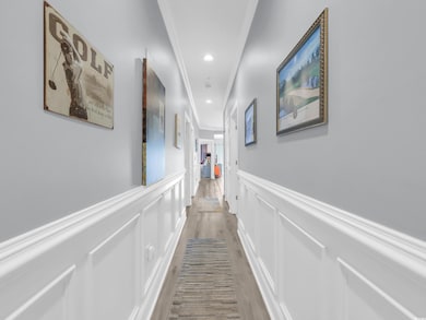 Hall featuring light wood-style floors, a wainscoted wall, a decorative wall, and recessed lighting