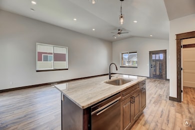 Kitchen with light stone countertops, open floor plan, stainless steel dishwasher, recessed lighting, and a kitchen island with sink
