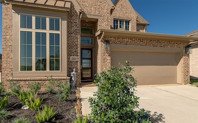 This modern brick home features a two-story design with large windows, enhancing natural light inside. It includes a spacious two-car garage and a well-maintained front garden, creating a welcoming entrance.