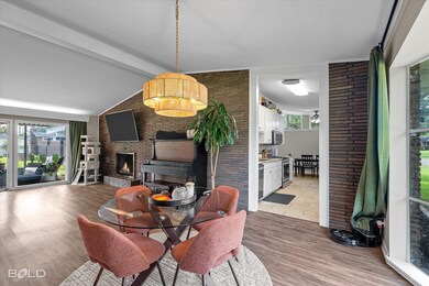 Dining area featuring brick wall, light wood finished floors, and a fireplace