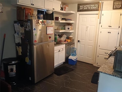 Kitchen with appliances with stainless steel finishes, dark marble finish flooring, white cabinetry, stone countertops, and open shelves