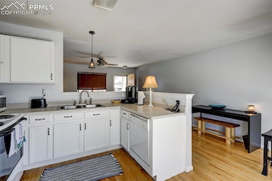 Kitchen with white appliances, a peninsula, a ceiling fan, and white cabinets