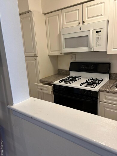 Kitchen featuring range, white cabinets, and dark countertops