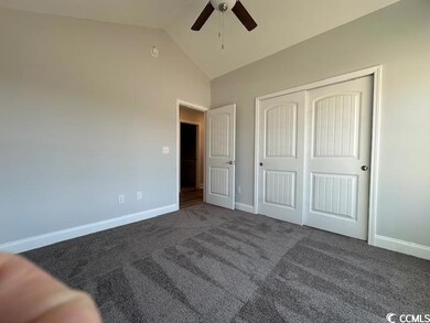 Unfurnished bedroom featuring baseboards, a ceiling fan, lofted ceiling, dark carpet, and a closet