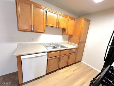 Kitchen featuring dishwasher, a sink, light counte
