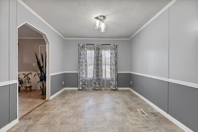 Spare room with crown molding, arched walkways, a textured ceiling, and a decorative wall