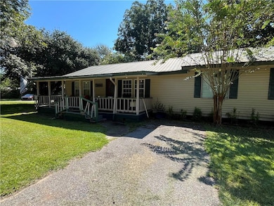 View of front of home featuring a porch, a front yard, and a metal roof