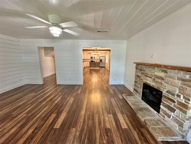 Unfurnished living room with dark hardwood / wood-style floors, ceiling fan, and a fireplace