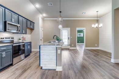 Kitchen with appliances with stainless steel finishes, hardwood / wood-style flooring, a center island with sink, and hanging light fixtures, Upgraded Shiplap wall in dining area and end of counter in kitchen, upgraded pendant lights over island