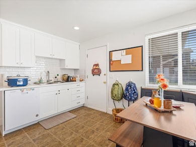 Kitchen with white cabinetry, dishwasher, decorative backsplash, light countertops, and recessed lighting