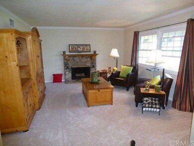 Spacious open living room. New carpet, new windows (window covering remains), crown molding, stone fireplace