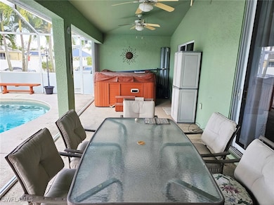 View of patio with glass enclosure, ceiling fan, and a pool with hot tub