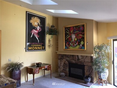 Light-filled living room features vaulted ceilings and skylights, and a gas log fireplace.