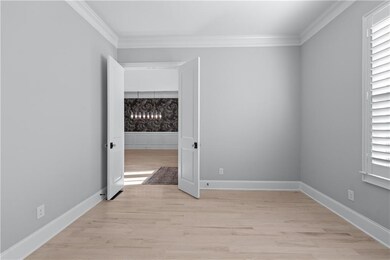 Unfurnished room with ornamental molding, a chandelier, light wood-type flooring, and baseboards
